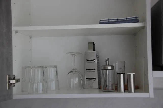 Küchenschrank mit Gläsern und Zubehör.