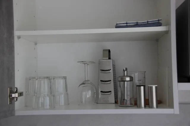 Küchenschrank mit Gläsern und Zubehör.