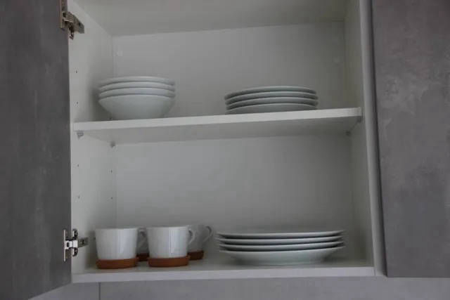 Küchenschrank mit Tellern, Tassen und Zubehör.