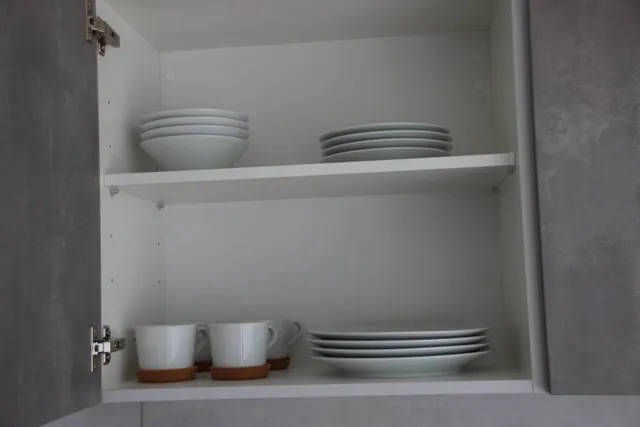 Küchenschrank mit Tellern, Tassen und Zubehör.