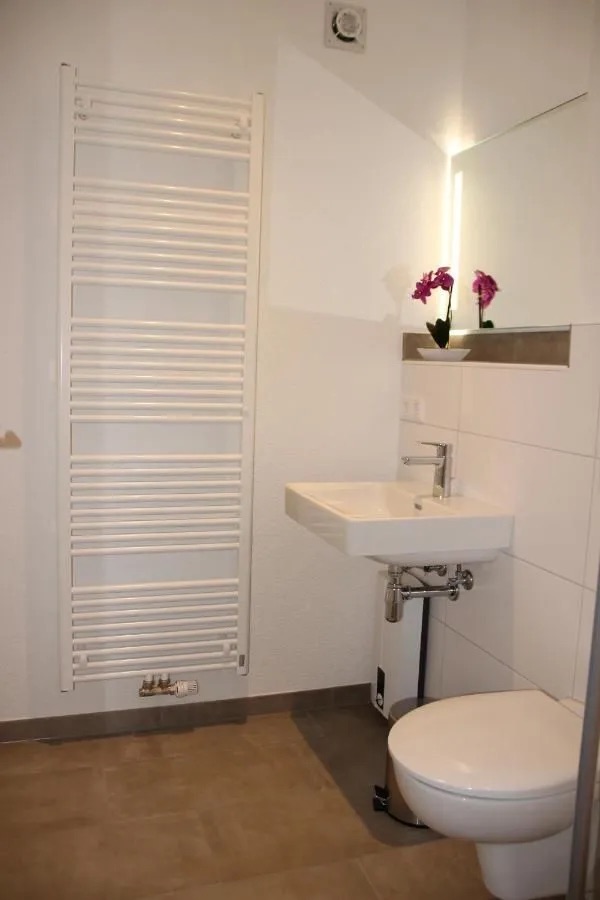 Bad mit Waschbecken, Toilette und Wandheizung.